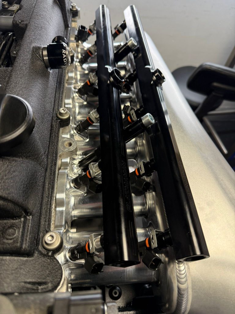 Close-up of two Plazmaman fuel rails on the intake runners, each feeding six injectors, one row nearer the cylinder head than the other