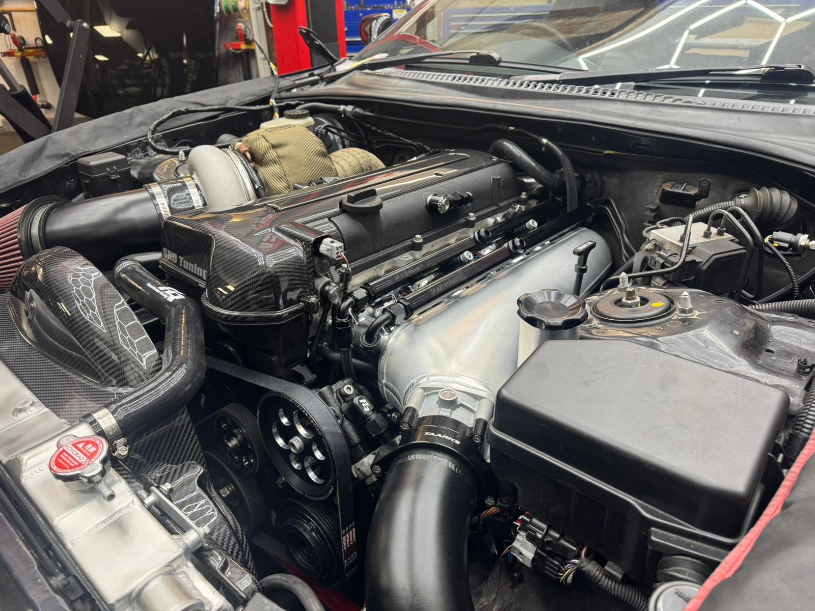 Supra 2JZ-GTE engine bay with a Plazmaman intake manifold and two black Plazmaman fuel rails running along the intake runners